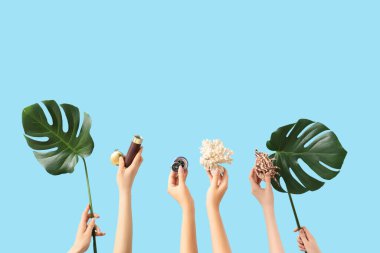 Mavi arka planda dürbün, pusula, kabuk ve canavar yapraklı kadın eller. Seyahat kavramı