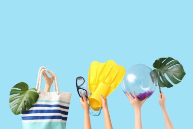 Yüzgeçli kadın eller, şnorkelli maske, şişme top, çanta ve mavi arka planda canavar yaprakları. Seyahat kavramı