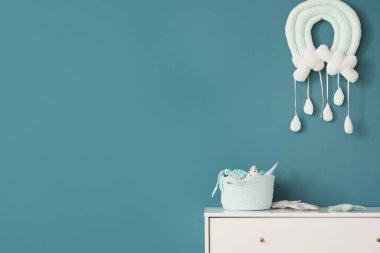 Mavi duvarın yanında içinde bebek oyuncakları olan sepet.