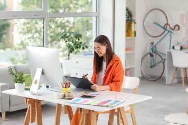 Ofiste tabletle çalışan genç bayan grafik tasarımcısı