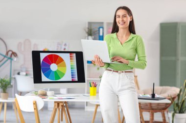 Young female graphic designer working with laptop in office