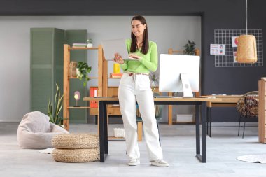 Young female graphic designer working with laptop in office