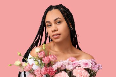 Pembe arka planda bir buket çiçekle güzel bir Afro-Amerikalı kadın.