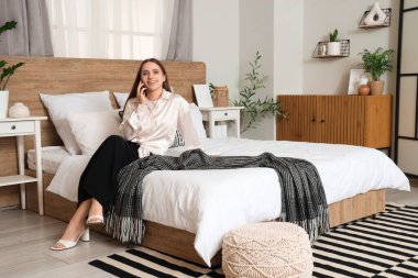 Yatakta telefonla konuşan genç ve güzel bir kadın.