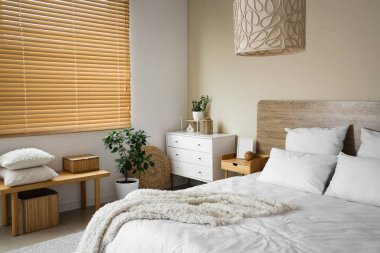 Rahat yatak, bank, çekmeceler ve yatak odasının içindeki dekoratif ağaç.