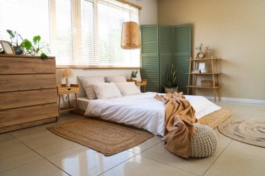 Rahat yatağı, çekmeceleri ve katlanır ekranı olan şık bir yatak odası.