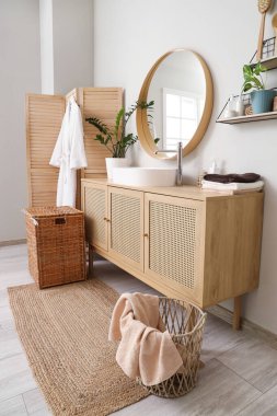 Modern lavabo, çekmeceler, katlanan ekran ve banyo içi çamaşır sepeti.