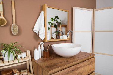 Modern lavabo, çekmeceler, banyonun içindeki kahverengi duvarın yanında katlanan ekran.