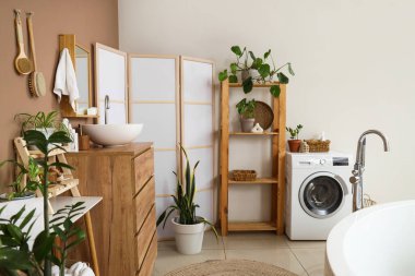 Modern lavabo, çekmeceler, banyo içindeki kahverengi duvarın yanındaki masa ve katlanan ekran.