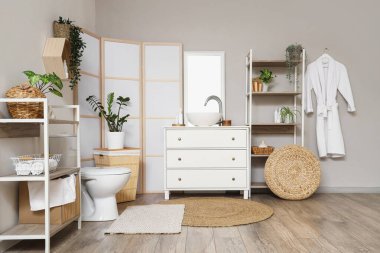 Lavabosu, klozeti ve raf ünitesi olan hafif bir banyo.