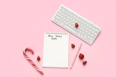 Yeni Yıl Hedefleri, klavye ve pembe arkaplanda Noel süslemeleri içeren defter