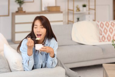 Evde lezzetli yoğurt yiyen güzel bir Asyalı kadın.