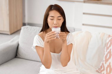 Evinde bir bardak lezzetli yoğurtla güzel bir Asyalı kadın.