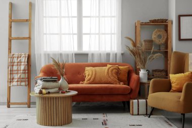 Oturma odasındaki kahve masasında sonbahar süslemeleri olan şık kıyafetler yığını.