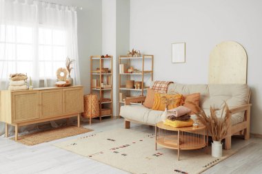 Oturma odasındaki kahve masasında sonbahar süslemeleri olan şık kıyafetler yığını.