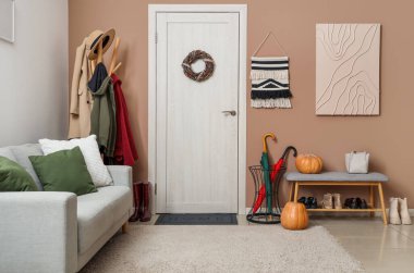 Koridorun içinde kapı, askılık ve kanepe var.