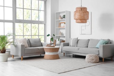 Interior of light living room with grey sofas, shelf unit and table clipart