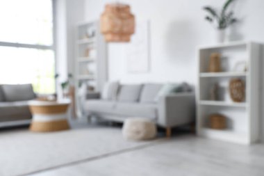 Bulanık oturma odası, gri koltuklar, raf üniteleri ve masa.