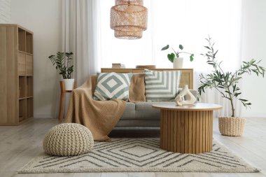 Gri kanepeli, masalı ve pencereli aydınlık oturma odasının içi.