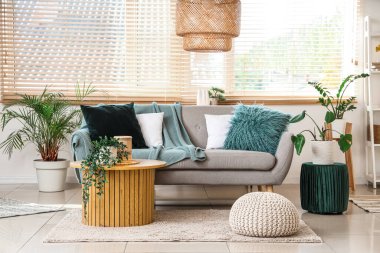 Gri kanepe, puf ve pencereli aydınlık oturma odasının içi.