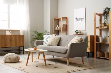 Gri kanepe, masa ve raf üniteleriyle aydınlık oturma odasının içinde.