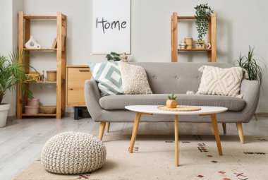 Gri kanepe, masa ve raf üniteleriyle aydınlık oturma odasının içinde.