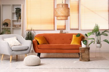 Kırmızı kanepesi, koltuğu ve penceresi olan bir oturma odası.