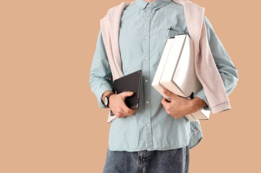 Tablet bilgisayarı ve bej arkaplanlı klasörleri olan genç işadamı, yakın plan