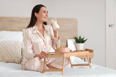 Pijamalı genç bir kadının evde kahvaltı yaptığı bir sabah.
