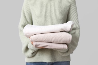 Gri arka planda kalın giysili kadın, yakın plan.