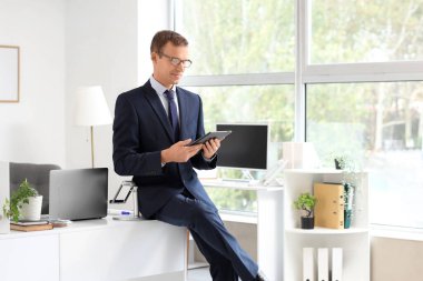 Handsome businessman working with tablet computer in office