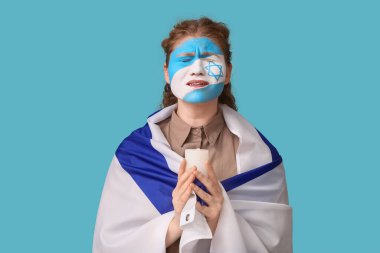 İsrail bayrağı taşıyan genç bir kadın ve yanan bir mum mavi arka planda dua ediyor. Uluslararası Soykırım Anma Günü