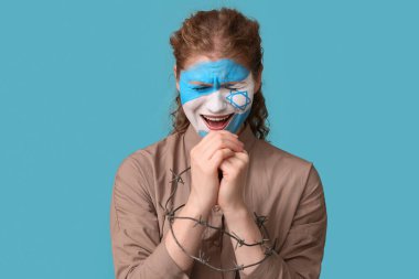 Yüzünde İsrail 'in boyalı bayrağı ve dikenli tellerle mavi arka plan için dua eden ağlayan genç bir kadın. Uluslararası Soykırım Anma Günü