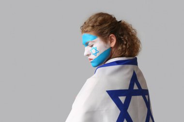 Young woman with painted face and flag of Israel on light background. International Holocaust Remembrance Day clipart