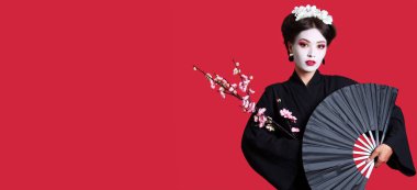 Beautiful young geisha holding fan and sakura on red background with space for text clipart