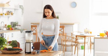 Mutfakta turuncu kesen genç kadın.