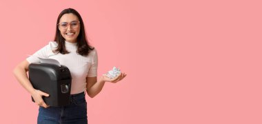 Sekreter kağıt öğütücüsünü pembe arkaplanda tutuyor.