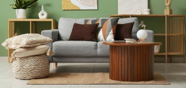 Yumuşak yastıklı gri kanepe ve şık oturma odasında ahşap masa.