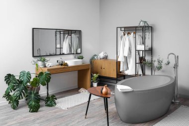 Banyonun içinde raf ünitesi, ayna ve gri küvet var.