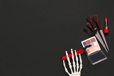 Ruj ve siyah arka planda Cadılar Bayramı dekoru olan farklı dekoratif kozmetik ürünler.