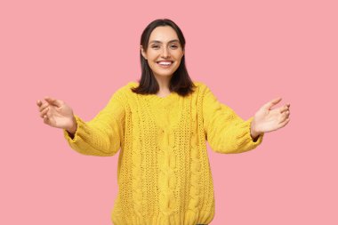 Genç bir kadın pembe arka planda sarılmaya hazır.