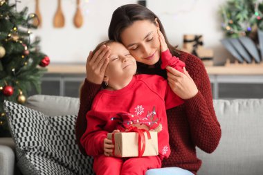 Genç anne ve küçük kızı Noel hediyesiyle evde.