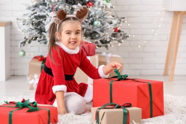 Noel Baba kostümlü, Noel arifesinde evde hediye kutularıyla sevimli küçük bir kız.
