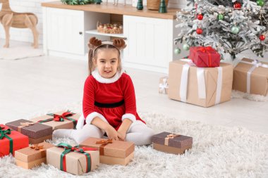 Noel Baba kostümlü, Noel arifesinde evde hediye kutularıyla sevimli küçük bir kız.