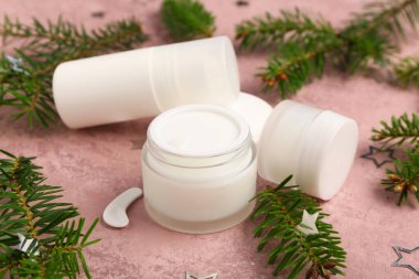 Şişe, kozmetik ürünlerin kavanozları ve pembe grunge arka planda köknar dallarıyla güzel bir kompozisyon, yakın plan.