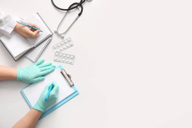 Beyaz zemin üzerinde not defteri ve pano olan doktor elleri