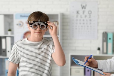 Göz çerçevesi ve göz doktoru olan küçük çocuk klinikte.