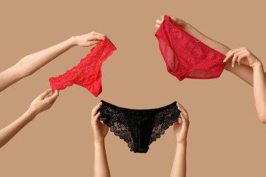 Bej arka planda farklı stil dantel külotlu kadın elleri, yakın plan.