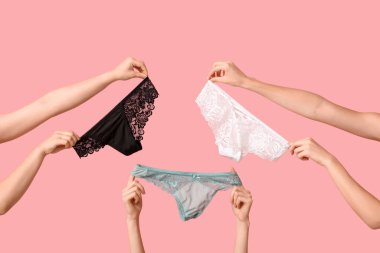 Pembe arka planda farklı stil dantel külotlu kadın elleri, yakın plan.