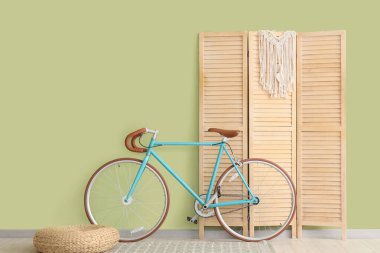 Katlanan ekran, puf ve bisiklet yeşil duvarın yanında.